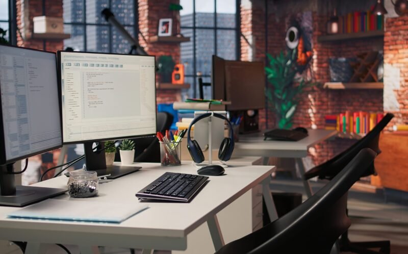 PC in startup office used to design and implement algorithms enabling machine learning. Technology unicorn venture workspace with PC used to conduct code reviews to fix bugs, jib down shot